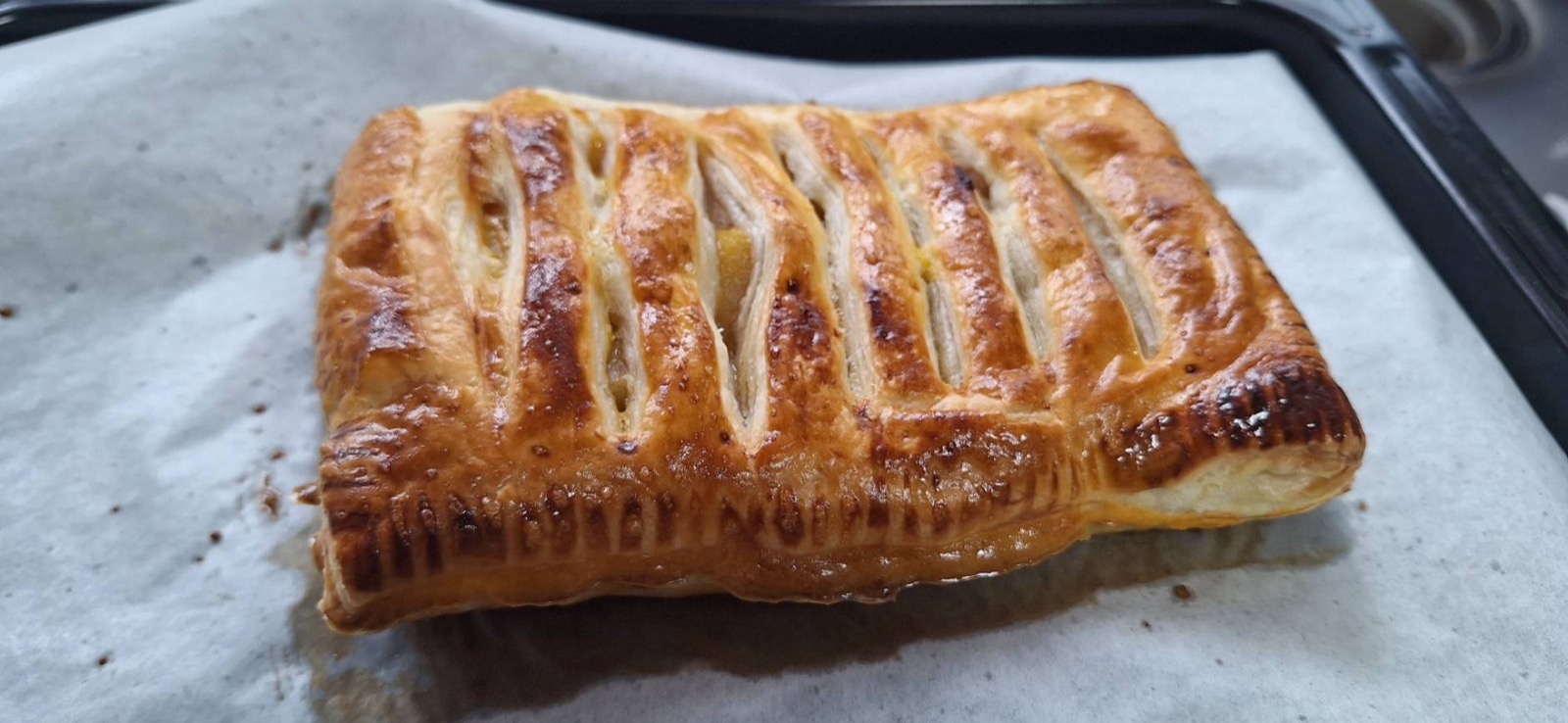 焼き上がったパイ生地のアップルパイ、切り込みからりんごが覗いている