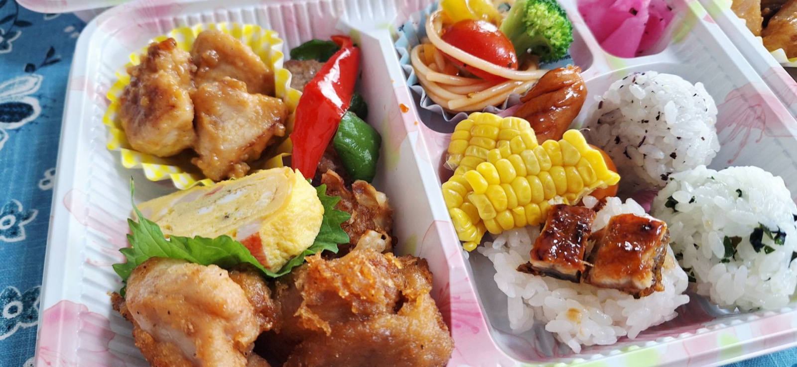 唐揚げ・卵焼き・うなぎ・コーンなどが彩りよく詰まったお弁当のアップ