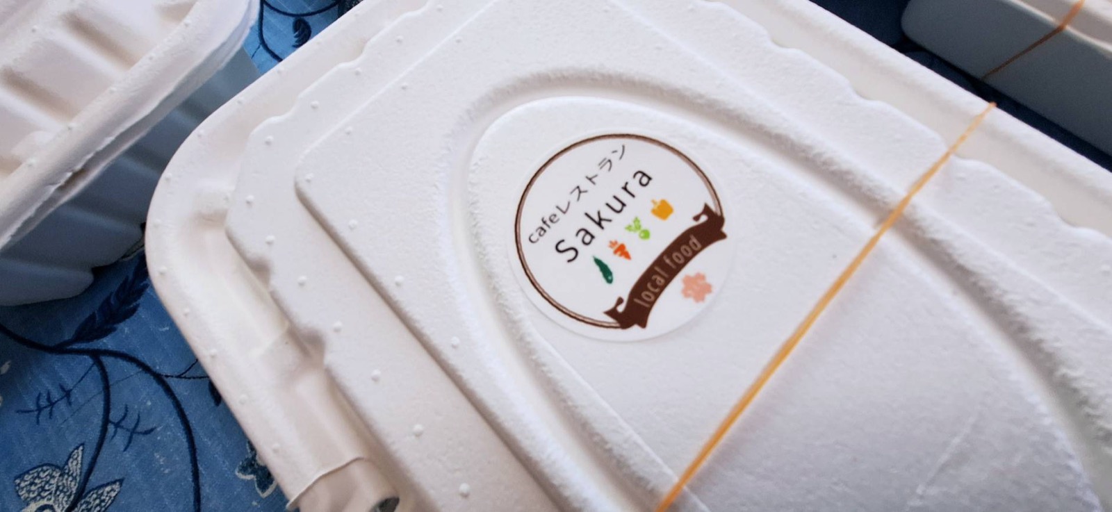 お弁当の蓋に貼られたcafeレストランSakuraのシール