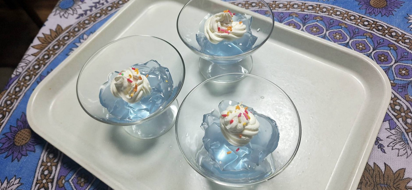 水色のジュレに生クリームとスプレーチョコをのせたデザート3つ