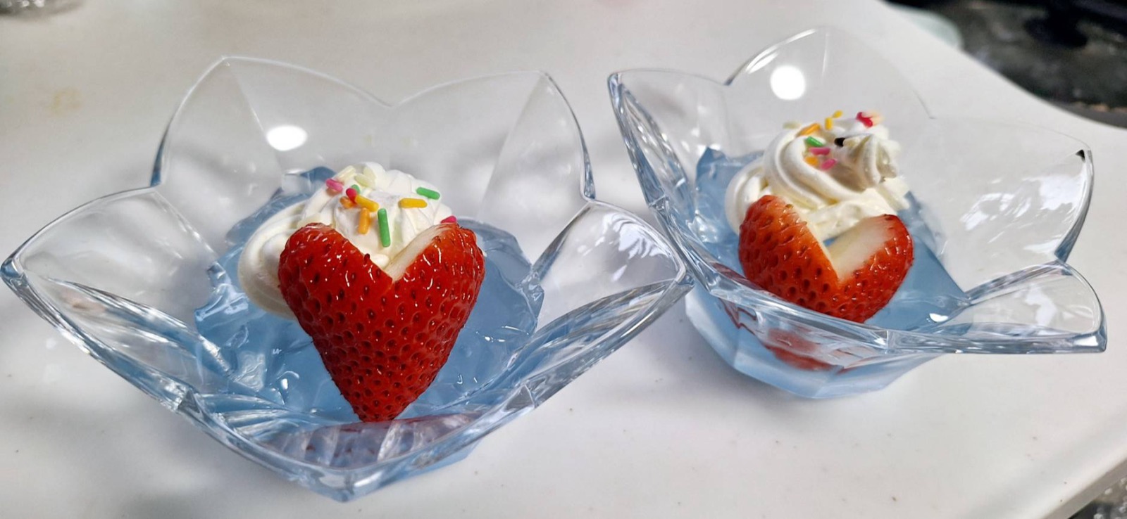 水色のジュレにいちごと生クリームをのせたデザート2つ