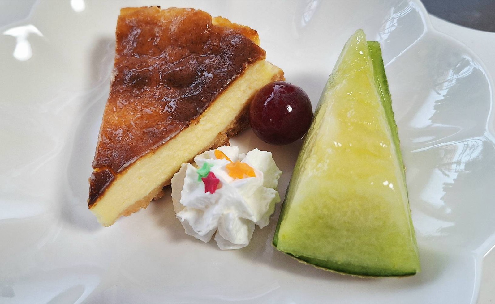 ベイクドチーズケーキとメロン、ぶどうを盛り合わせたデザートプレート