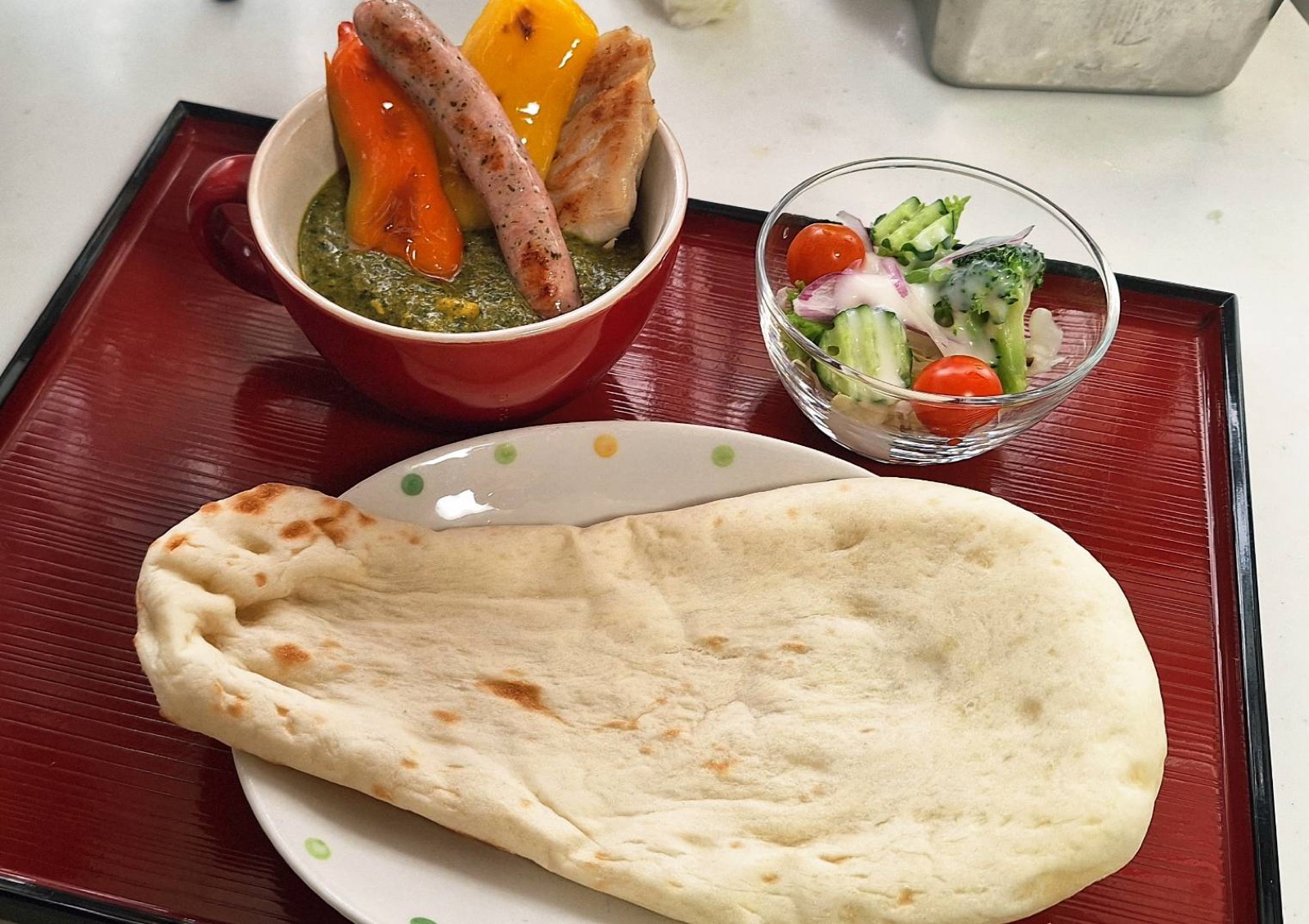 ソーセージとパプリカをのせたグリーンカレーとナン、サラダのセット