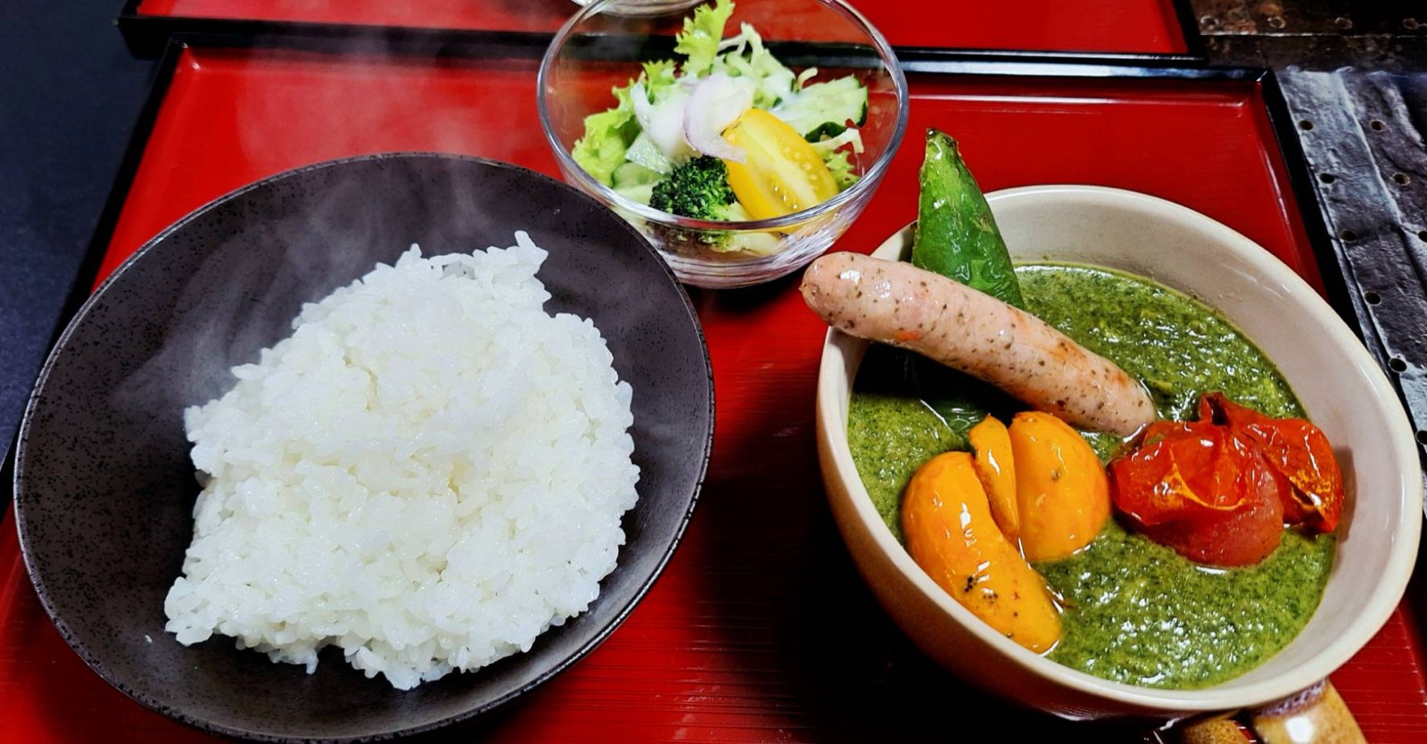 ソーセージとパプリカをのせたグリーンカレーとライス、サラダのセット