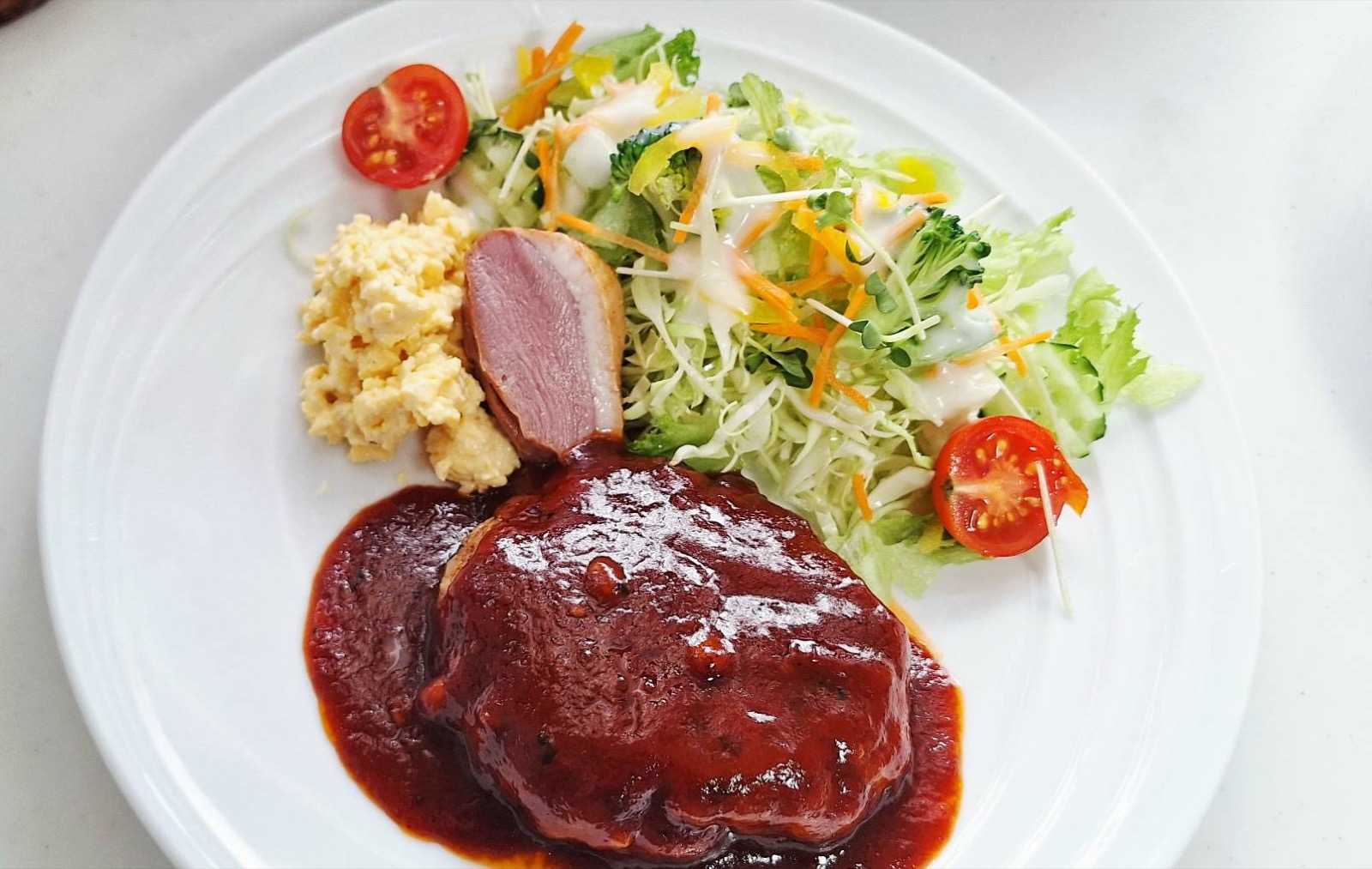 ハンバーグにサラダとスクランブルエッグを添えたランチプレート