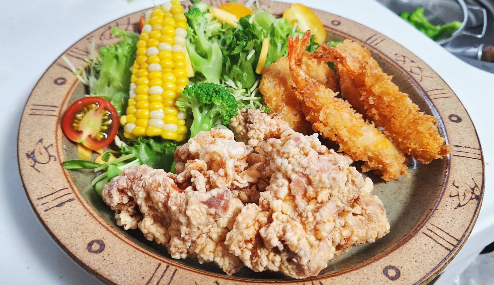 唐揚げとエビフライ、コーンやブロッコリーなど彩り野菜が盛られたプレート