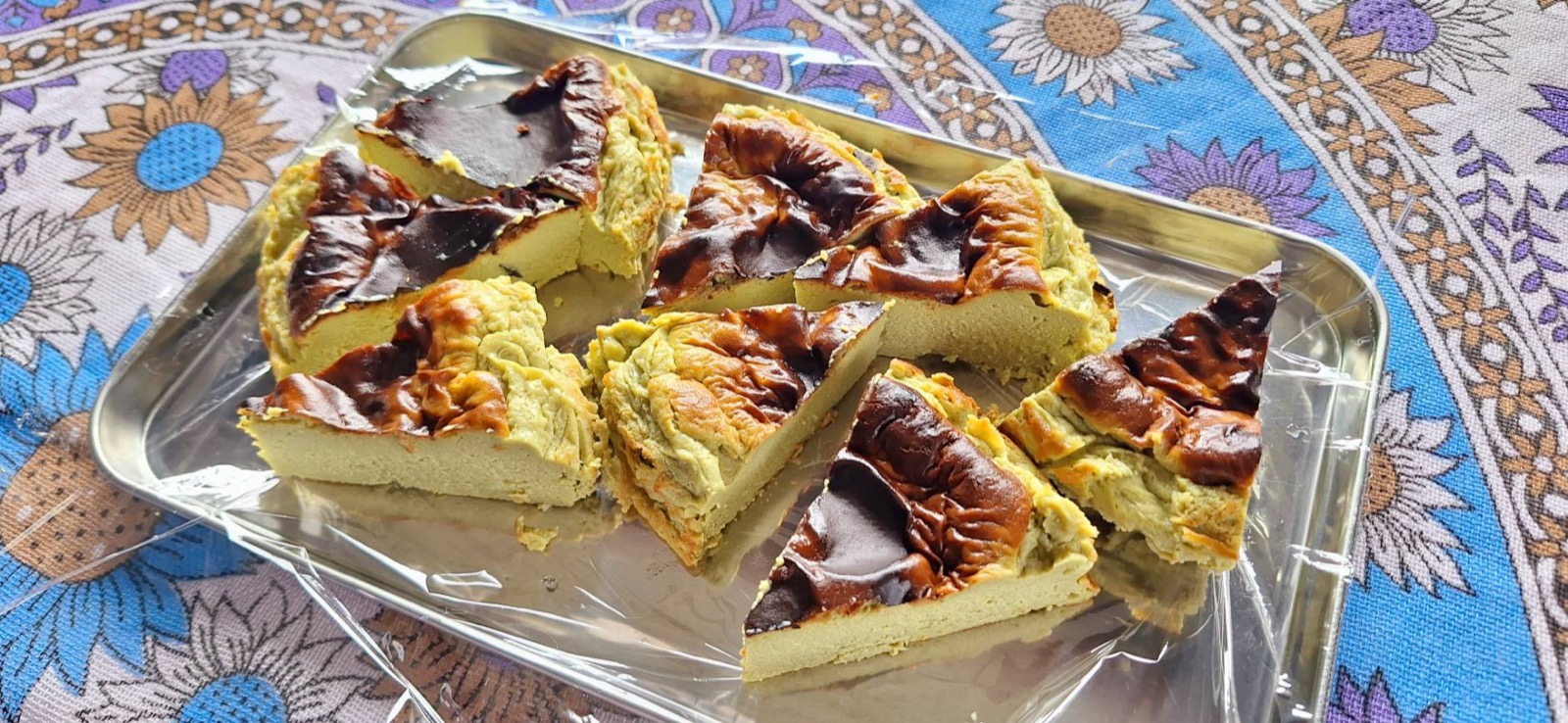 焦げ目のついた濃厚抹茶のバスクチーズケーキを三角形にカットしてトレイに並べたもの