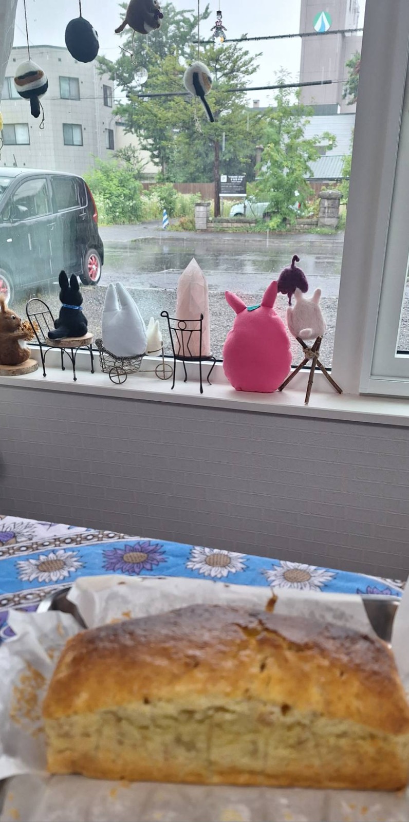 窓の外は土砂降りの雨、手前に焼き上がったバナナケーキ