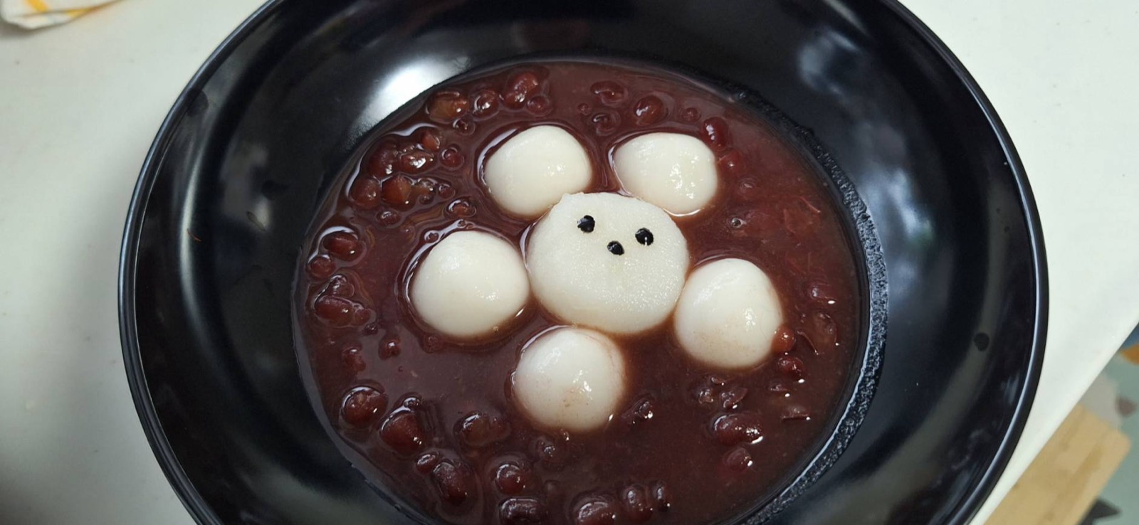黒いお椀の白玉ぜんざい、白玉がシマエナガの顔になっている