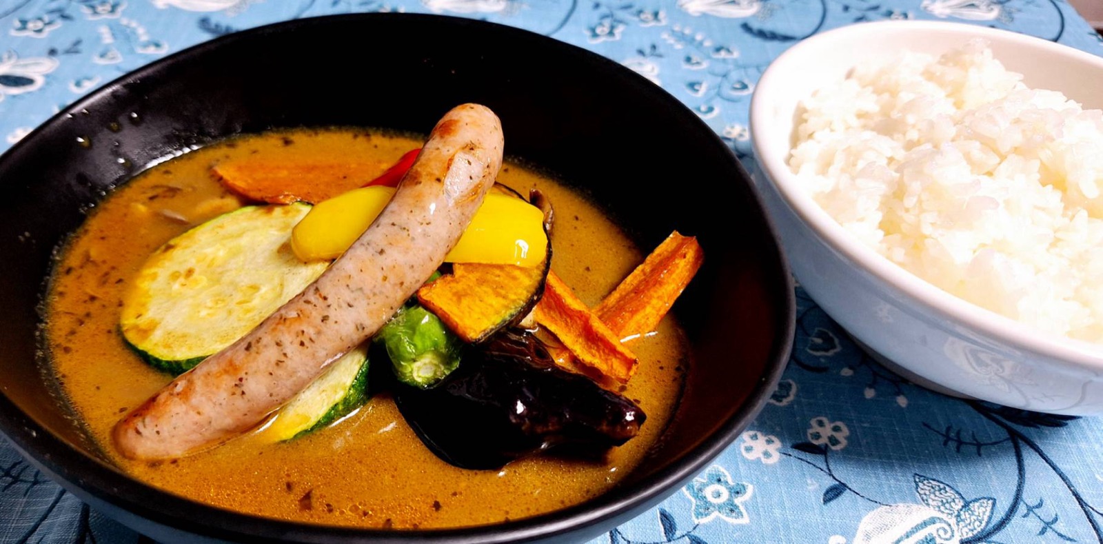 ソーセージとズッキーニ、パプリカなど野菜がたっぷり入ったスープカレーとご飯